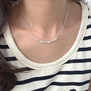 Close-up of minimalist S925 sterling silver snake chain with irregular pendant on a model