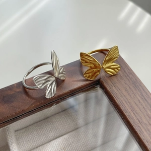 Macro detail of silver and gold butterfly wing rings on a wooden display stand
