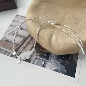 Dettaglio della collana di perle d'argento con ciondolo a sorriso su piatto ceramica