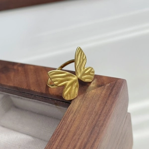 Close-up of golden butterfly ring with detailed engraved wings on a wooden box
