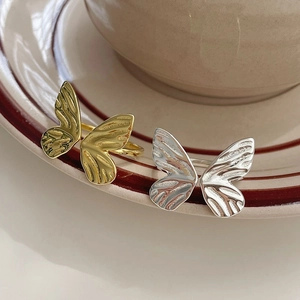 Elegant gold and silver S925 sterling silver butterfly open rings on a ceramic cup