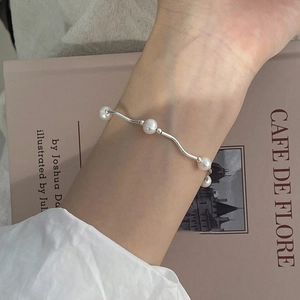 Elegant 925 silver wave bracelet with white freshwater pearls worn on a female wrist