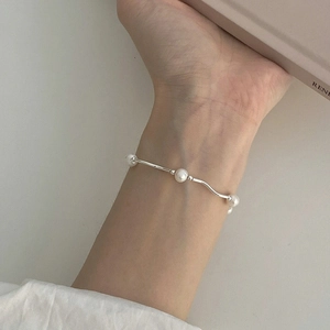 Close-up of 925 sterling silver wavy bracelet featuring three natural freshwater pearls