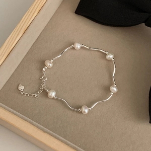 Elegant 925 sterling silver wavy bracelet with natural freshwater pearls on beige velvet