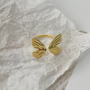 Close-up of golden butterfly ring with textured wings and adjustable open band