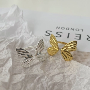 Detailed close-up of butterfly rings in gold and silver finish on artistic paper