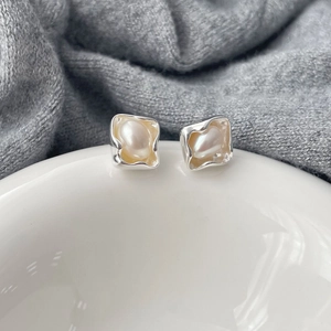 Detailed macro view of irregular natural pearls set in silver baroque stud earrings