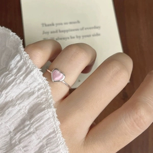 Close-up of a pink heart cat-eye stone ring on a model's finger with a gift card