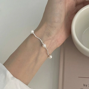 Close-up of S925 sterling silver wavy pearl bracelet worn on a female wrist in daily scene