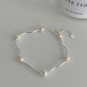 Detailed shot of freshwater pearl bracelet with wavy silver tubes and a heart charm