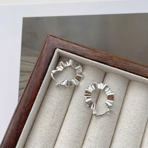 Macro detail of S925 sterling silver hoop earrings with modern pleated texture finish
