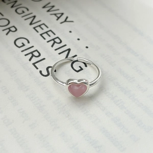 Close-up of S925 sterling silver heart ring with pink cat eye stone on a magazine
