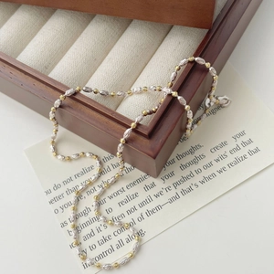 Élégant collier de perles bicolores or et argent posé sur un écrin à bijoux en bois