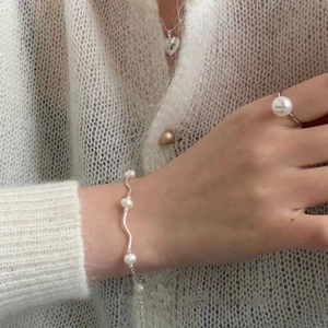Macro detail of wave silver bracelet with natural freshwater pearls on knit background