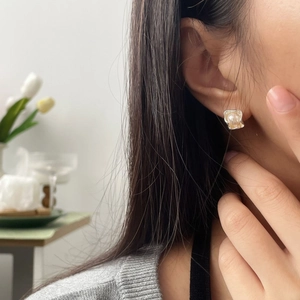 Macro side view of irregular natural pearl stud earring on model with silver metal edges