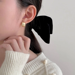 Boucles d'oreilles carrées en or avec texture brossée portées par un mannequin