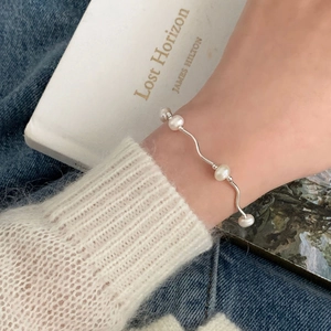 Detail showing wavy 925 sterling silver chain and freshwater pearls on a woman's wrist