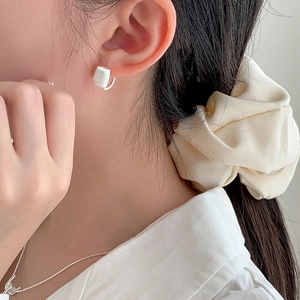 Détail de boucles d'oreilles carrées géométriques avec finition en argent mat brossé
