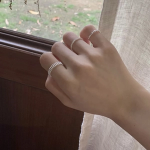 Close-up of three-piece silver ring set with bead texture worn on a hand by a window