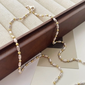 Détail du collier bicolore avec perles dorées et argentées aux textures ovales fines