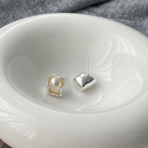 Minimalist square silver studs with round white pearls displayed in a ceramic bowl