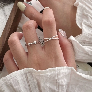Detail von S925 Sterlingsilber Herz- und Kreuzringen an der Hand mit Spitzenärmeln