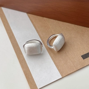 Vue détaillée de boucles d'oreilles carrées avec texture argentée mate brossée