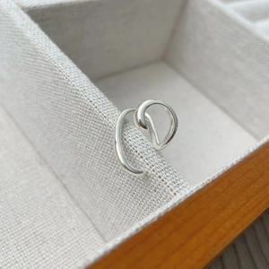 Macro detail of S925 sterling silver ear cuff with irregular double-layer streamline lines