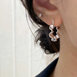 Close-up of S925 sterling silver earring with textured wavy folds and cubic zirconia stud