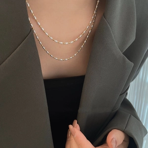 Gros plan d'un collier superposé bicolore avec perles d'olive texturées et détails en métal