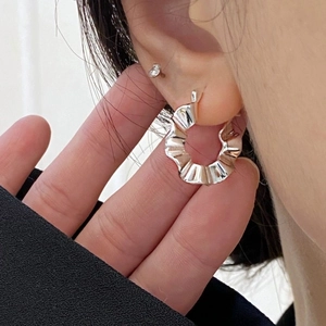 Macro shot of silver ruffled texture earrings showcasing modern metallic design details
