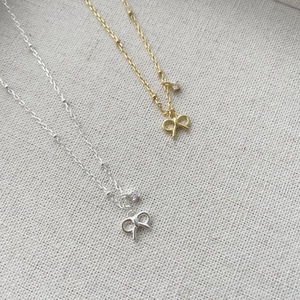 Macro shot of silver and gold bow pendant necklaces with cubic zirconia details
