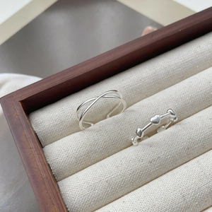 Minimalistischer S925 Silber Herzring und Kreuzlinien-Ring auf Canvas-Schmuckbox