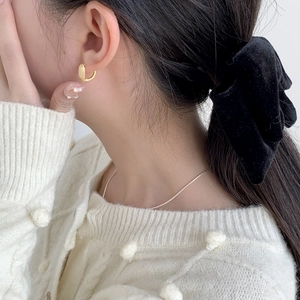 Gros plan d'élégantes créoles carrées dorées portées par un mannequin pour un look minimaliste