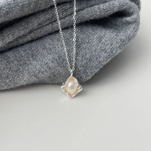 Irregular geometric silver necklace with natural pearl pendant on gray fabric