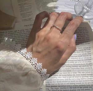 Detail of s925 silver beaded chain ring on finger with elegant book background