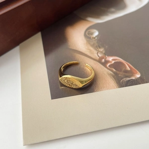Gros plan d'une bague soleil vintage dorée posée sur un fond artistique