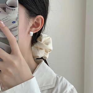Gros plan de boucles d'oreilles carrées blanches minimalistes sur un modèle élégant