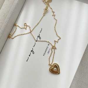 Macro detail of a 18K gold heart pendant necklace with a centered sparkling zircon stone