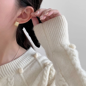 Boucles d'oreilles carrées dorées mates portées avec un pull en maille blanc cassé
