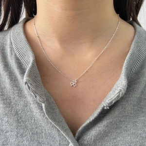Close-up of S925 sterling silver bow pendant with cubic zirconia on model neck