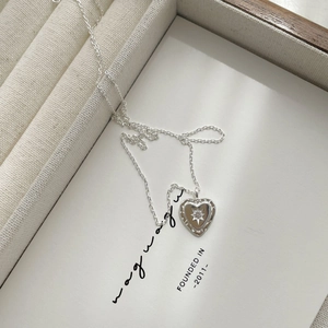 Macro detail of S925 sterling silver heart necklace with starburst engraving and small diamond