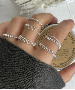 Close-up of a layered S925 silver ring set with chain and heart details on a hand