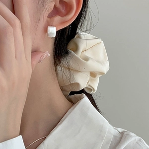 Gros plan de boucles d'oreilles carrées en argent S925 mat portées par un mannequin en douceur