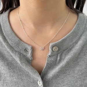 Close-up of S925 silver bow necklace with small sparkling zircon worn by female model