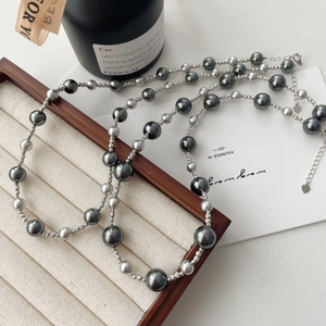 Close-up of double-layer gray pearl necklace with heart pendant on wooden jewelry tray
