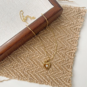 Close-up of golden heart pendant with engraved star and cubic zirconia on woven fabric