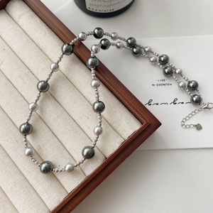 Detail of S925 silver clasp and gray gradient pearl necklace on a wooden tray
