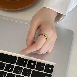 Gros plan d'une bague chevalière dorée minimaliste au doigt dans un environnement de bureau