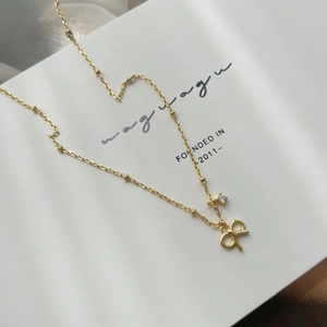 Detail of S925 silver bow necklace with gold finish and sparkling cubic zirconia pendant